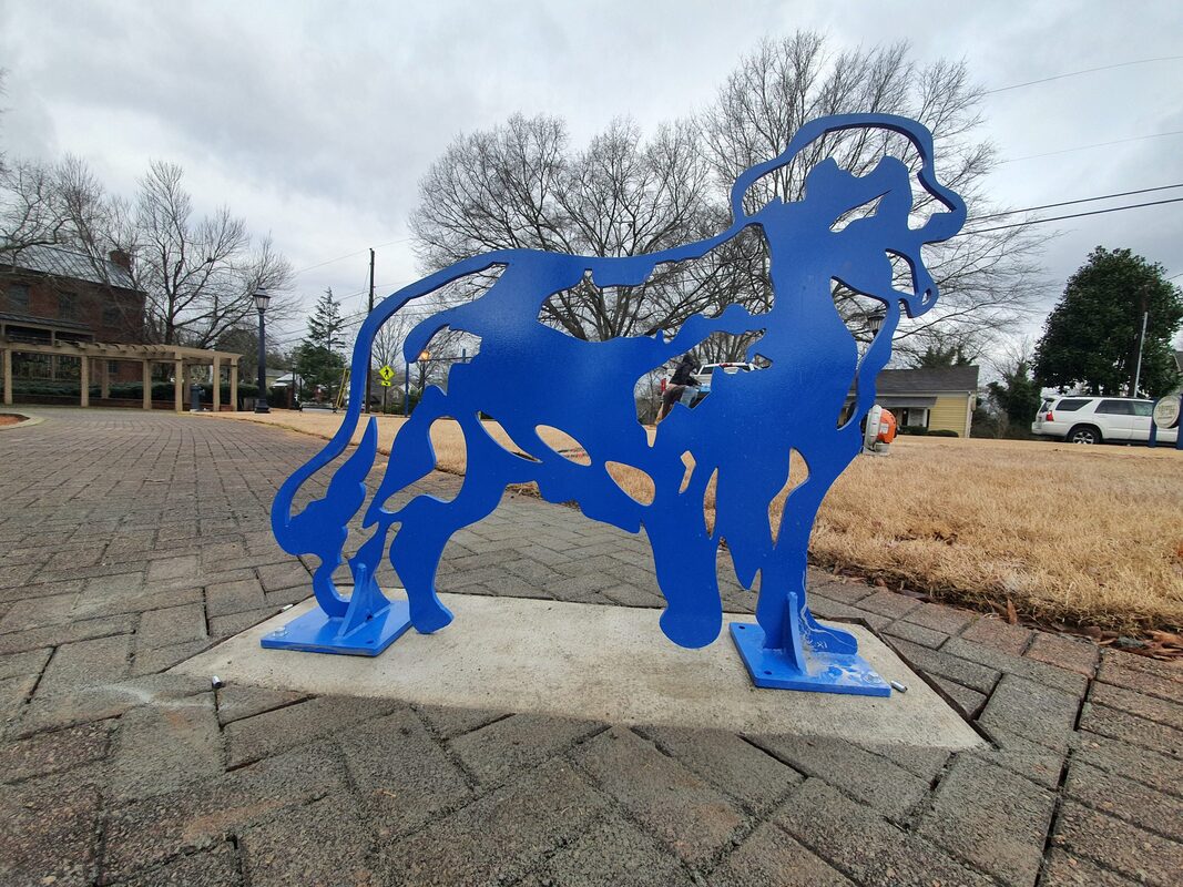 Golden Blue Guard Dog Bike Rack by Joe Norman and the National Sculptors' Guild placed in Roswell, GA, 2019. Features a Golden Retriever Dog cutout of Stainless Steel, painted royal blue. The dog can 