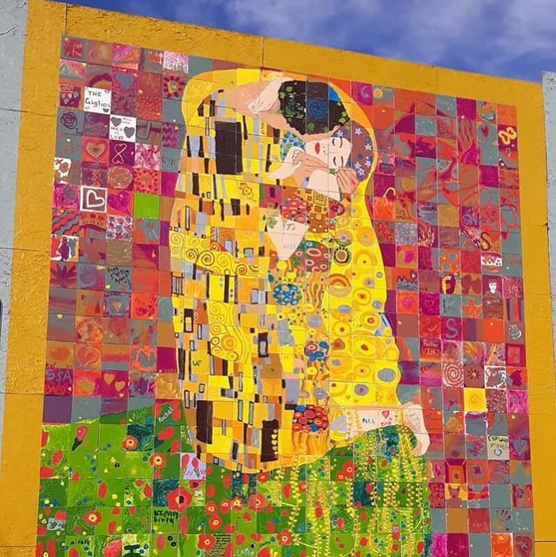 Make sure you check out the latest community mural by our artist Scott Freeman while visiting Loveland’s art scene.

“THE KISS” – Loveland Version, 15 x 15 feet. Feb,2020.

“2020 is our fourth year to create a giant community art piece in downtown Loveland, Colorado. For the design each year I’ve spoofed a famous fine art painting, giving each one a Valentine’s Day twist and a nod to Loveland.

This year I chose Austrian painter, Gustav Klimt, and his iconic 1908 painting, The Kiss. If you look closely you can see Dan Cupid aiming his arrow at the couple. Dan Cupid is the character who shows up in the special postmark each year for Loveland’s famous valentine re-mailing program. He’s kind of a Loveland mascot, at least around Valentine’s Day, so he made his way into the design this year.”  -Scott Freeman

#CommunityMural #ScottFreeman #Loveland #Colorado #TheKiss #Klimt #GustavKlimt #AfterKlimt #AroundLoveland #PaintByPanel #Mural #DowntownLoveland #Art #Community @ Loveland, Colorado